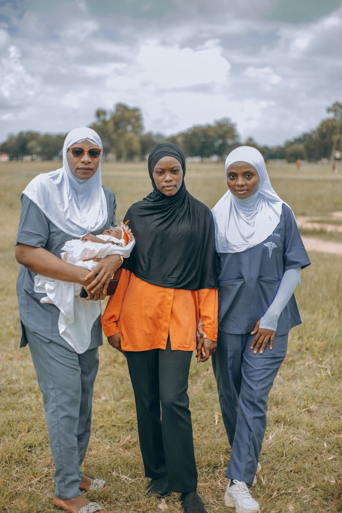 A family of four in traditional attire posing in an open field in Nigeria.